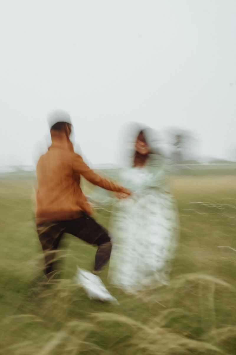 Motion-blurred photo of two people dancing and spinning in a grassy field.