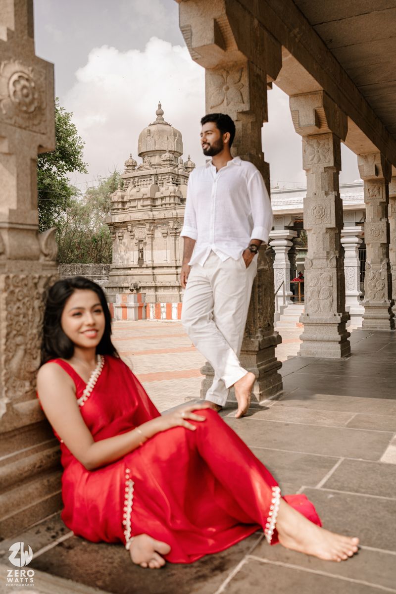 A couple in traditional Indian attire poses amid ornate temple pillars and architecture.