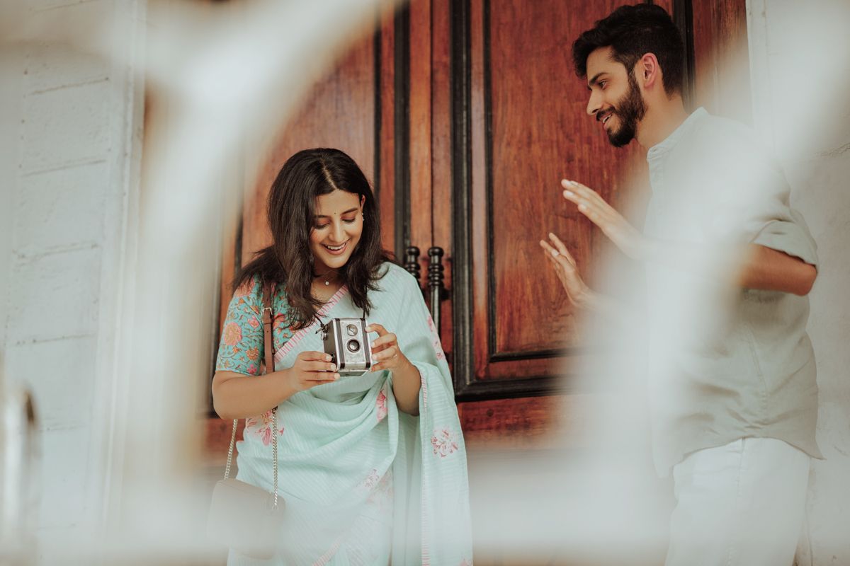 Through a soft vignette view, two people share a candid moment of joy and laughter in front of a wooden door.