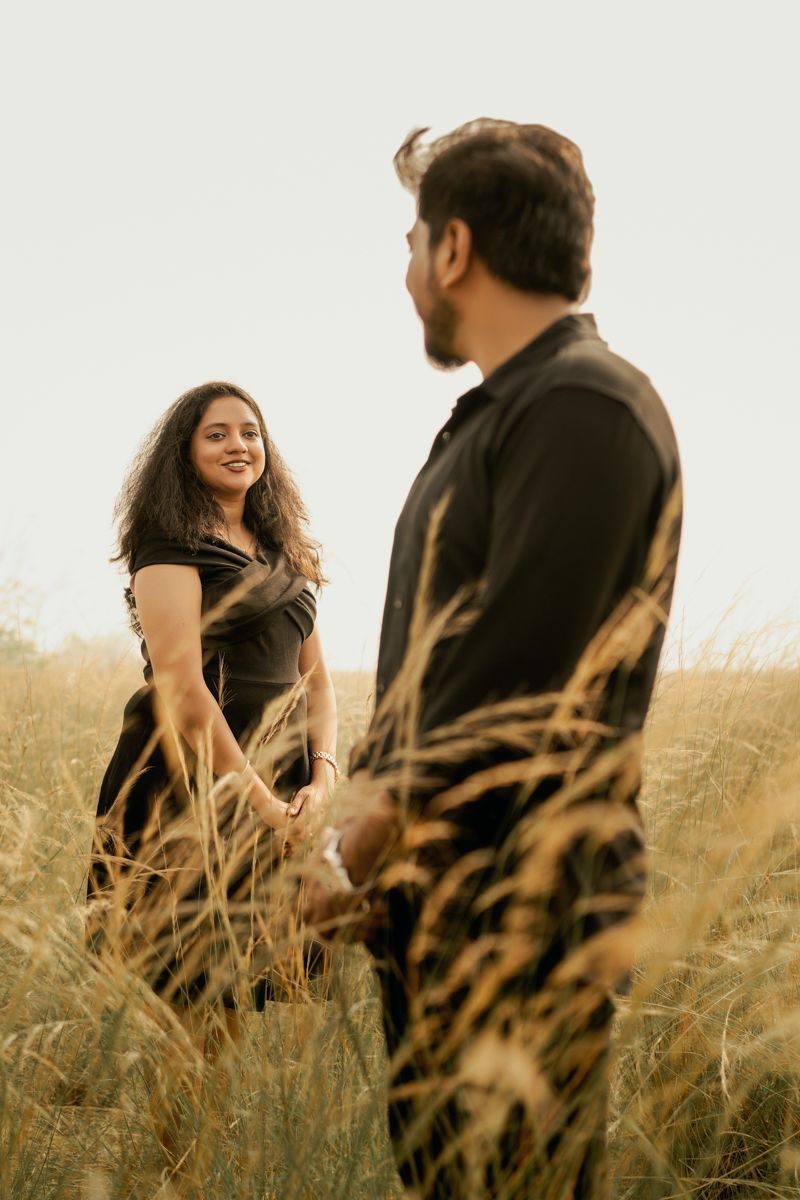 Happy couple enjoying a moment together in tall grass during golden hour.