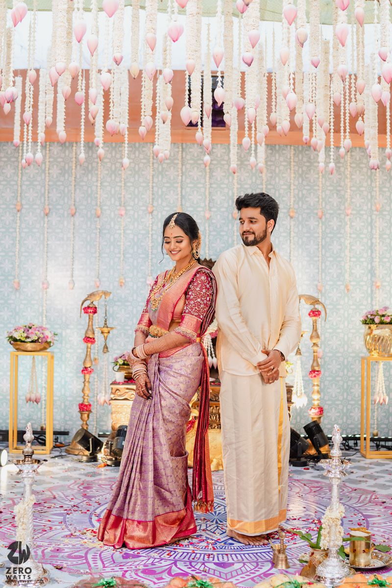 Traditional South Indian wedding ceremony with decorative hanging floral elements and brass decor.