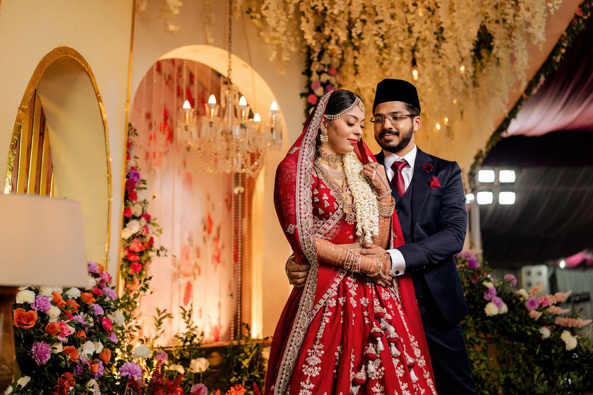 Elegant wedding setup with romantic arched backdrop decorated with cascading flowers and warm lighting.