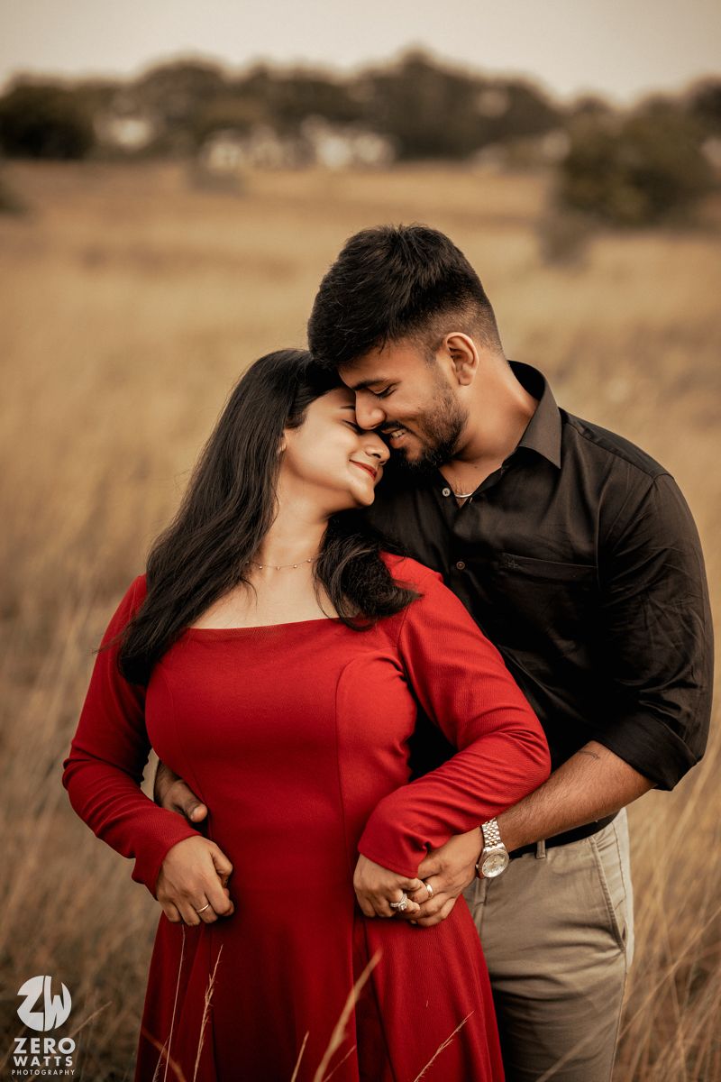 A romantic portrait of a couple in coordinated outfits embracing in a golden field.