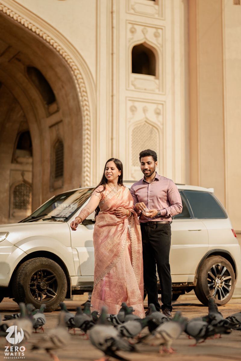 Romantic photo session with a couple posing near luxury cars in a classical architectural setting.