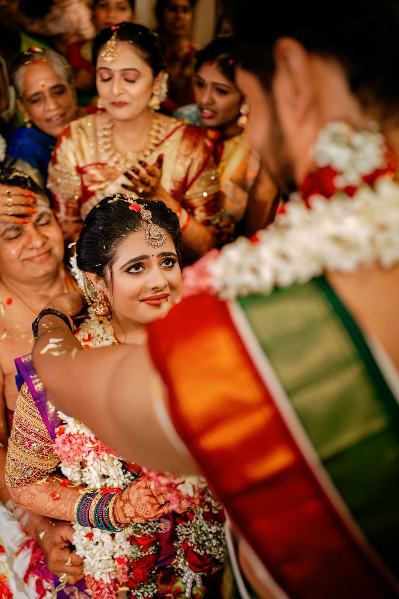 Traditional South Indian wedding ritual with bright silk sarees and ornate jewelry during ceremony.