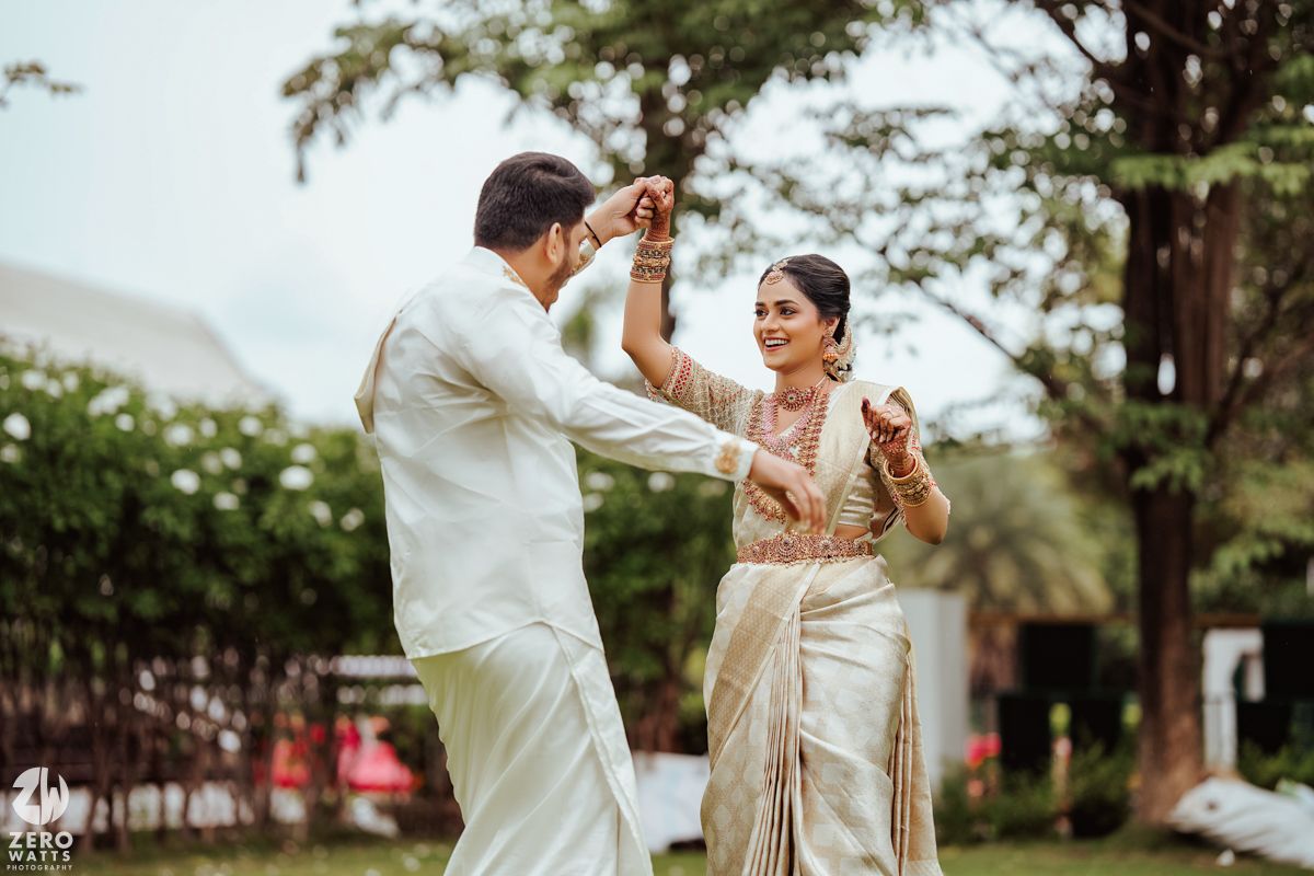 Couple performing romantic dance moves in traditional outfits on grass.