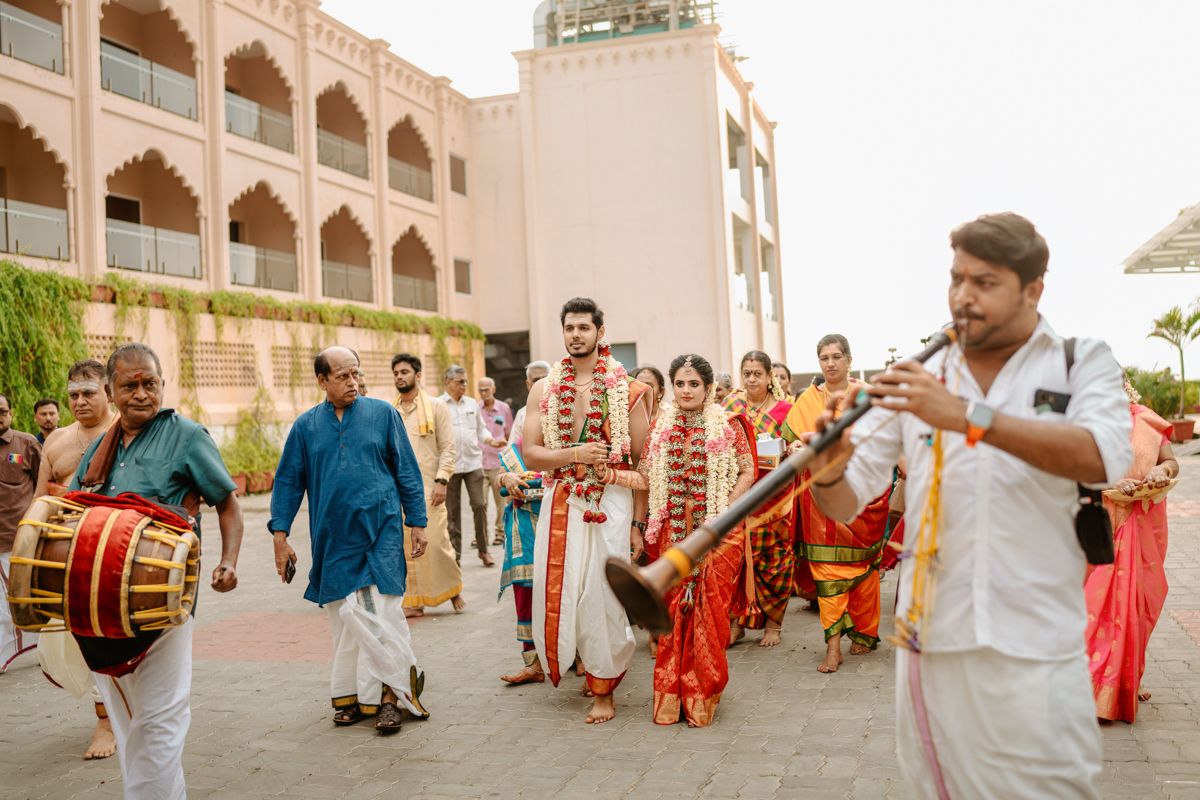 Musicians play traditional instruments during an Indian wedding celebration outside an ornate building.
