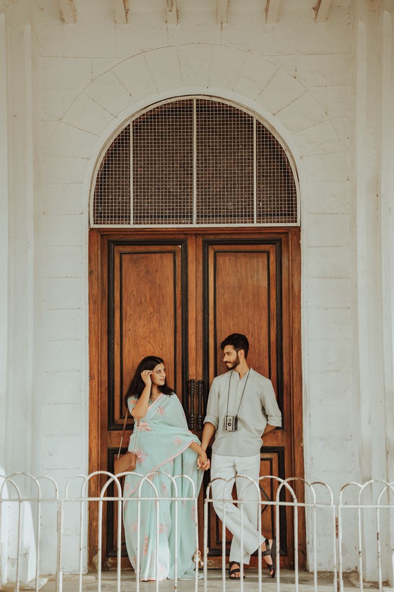 A dreamy portrait session in front of an ornate wooden door with arched architecture.