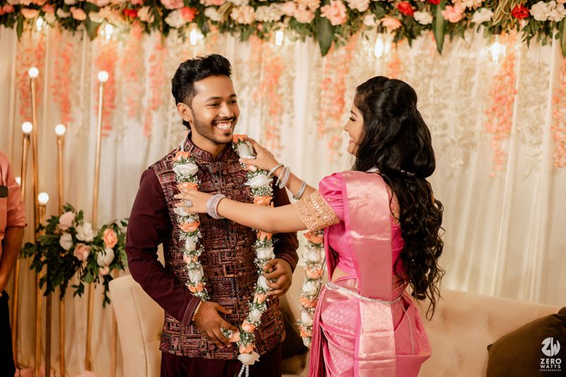 A couple sharing a joyful moment during their engagement ceremony with floral decor and soft lighting in the background.