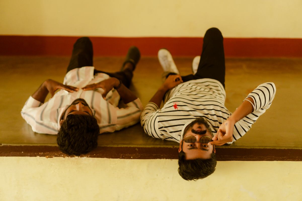 Two people relaxing on a wooden floor lying in opposite directions wearing casual clothes.