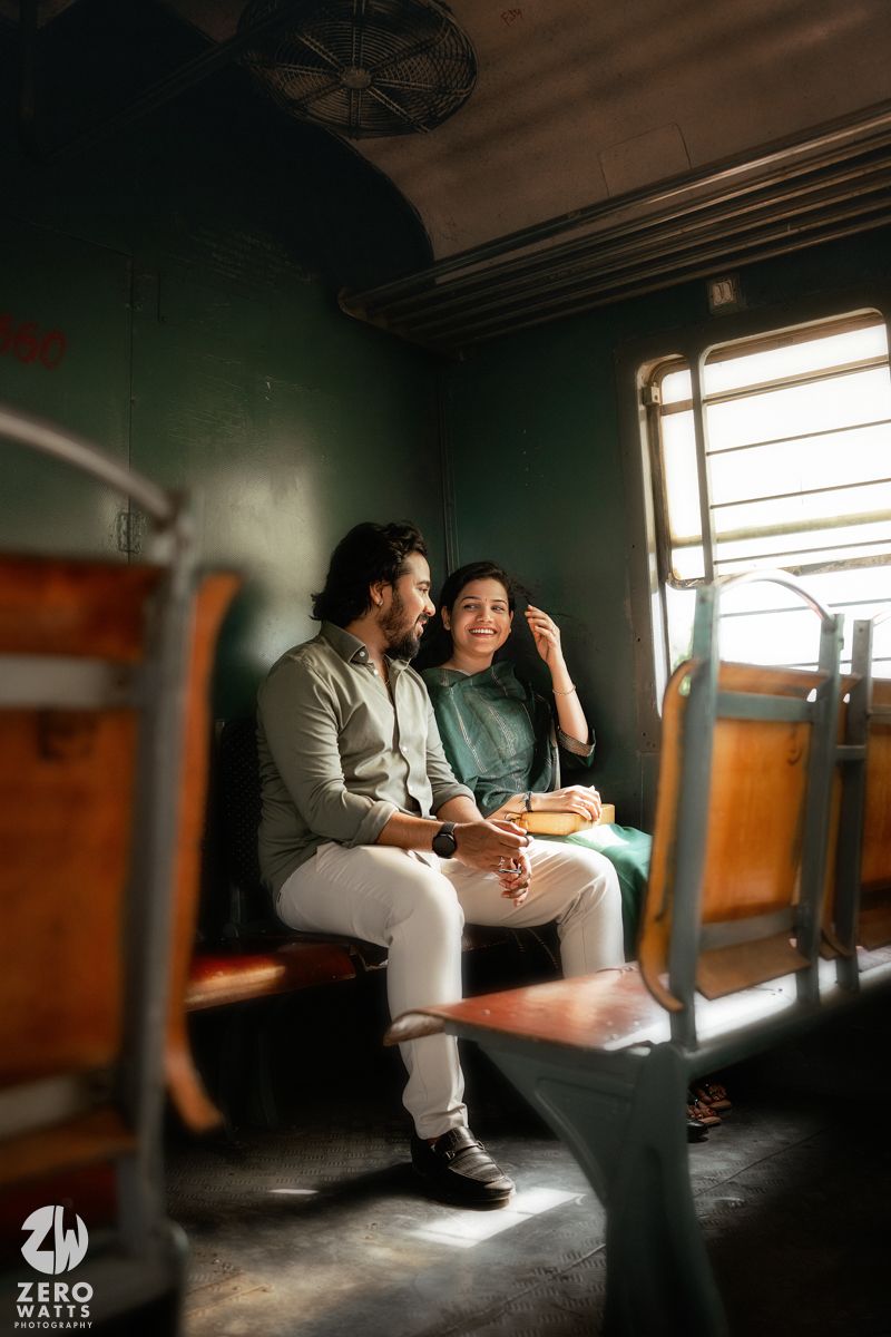 Romantic couple sharing tender moments in a dimly lit train compartment with sunlight streaming through windows.