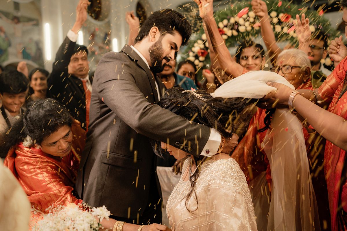 Wedding guests throw confetti during an indoor celebration as the couple shares a moment.