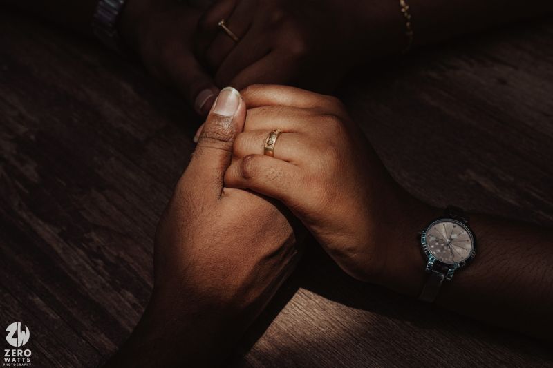 Close-up shot of hands wearing jewelry in dim lighting creating a moody atmosphere.