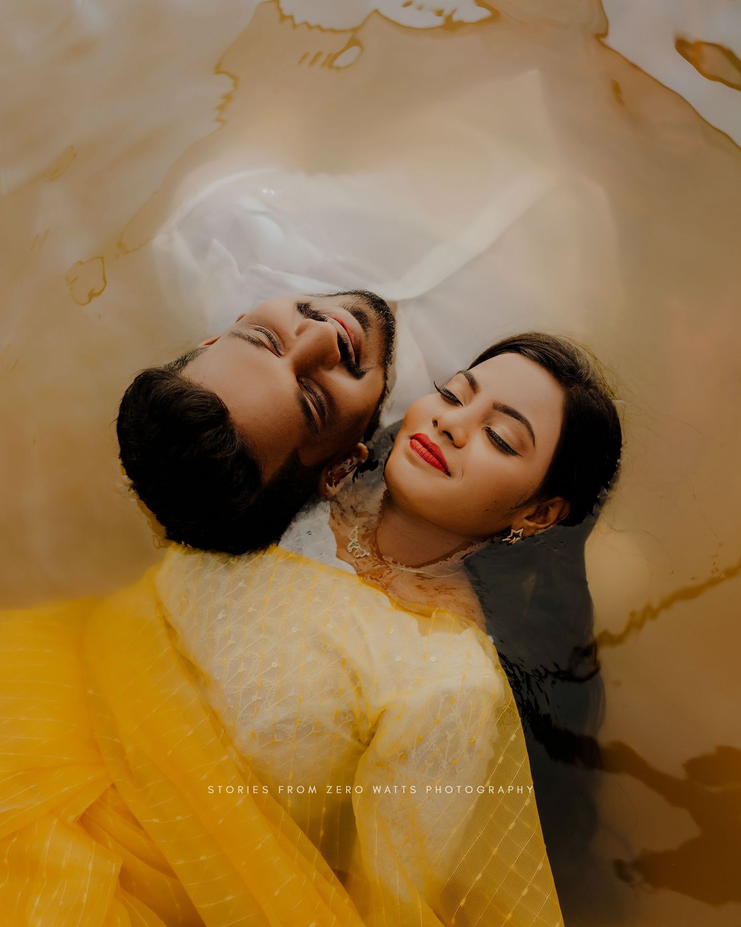 Two people relaxed with closed eyes lying on a yellow surface in artistic creative portrait photography.