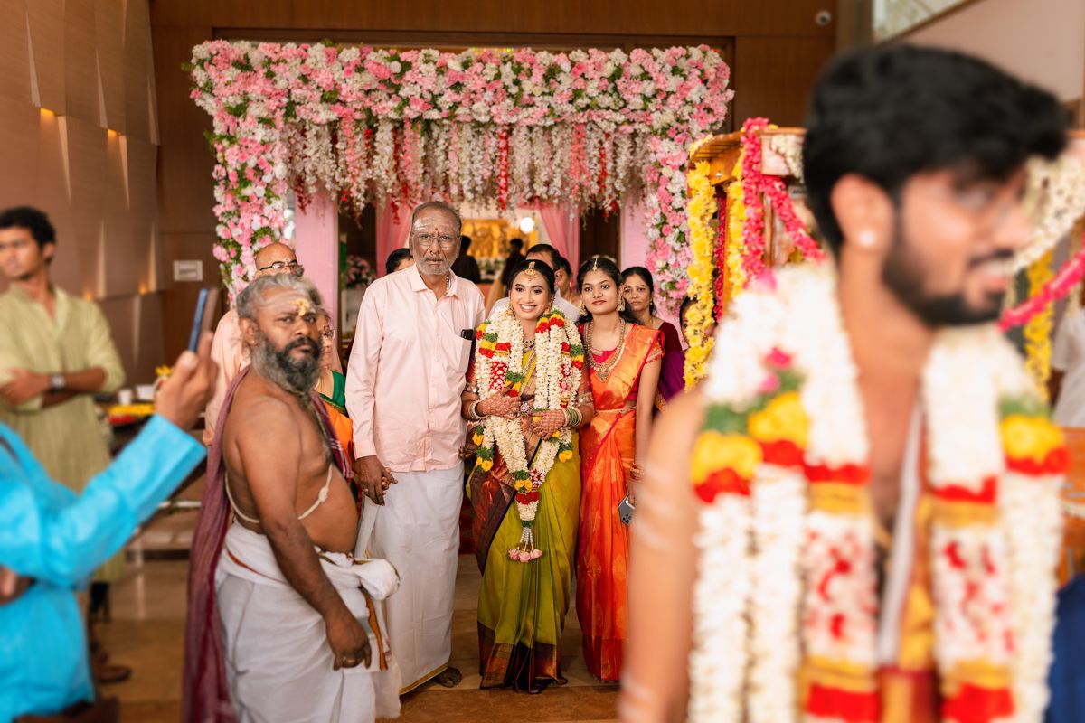 Traditional Indian wedding ceremony with guests gathered around floral mandap decorated in pink and white blooms.