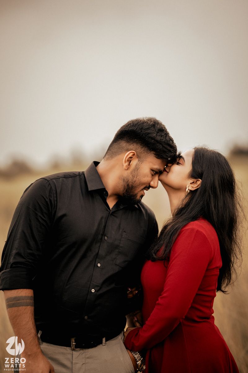 A tender moment between a couple sharing laughter and touching foreheads outdoors.