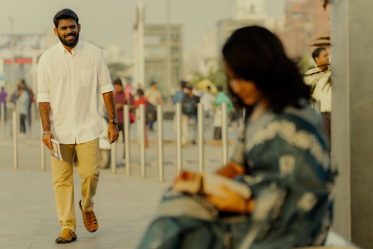 People relaxing at an outdoor urban station area with yellow pants and dress visible in muted tones.