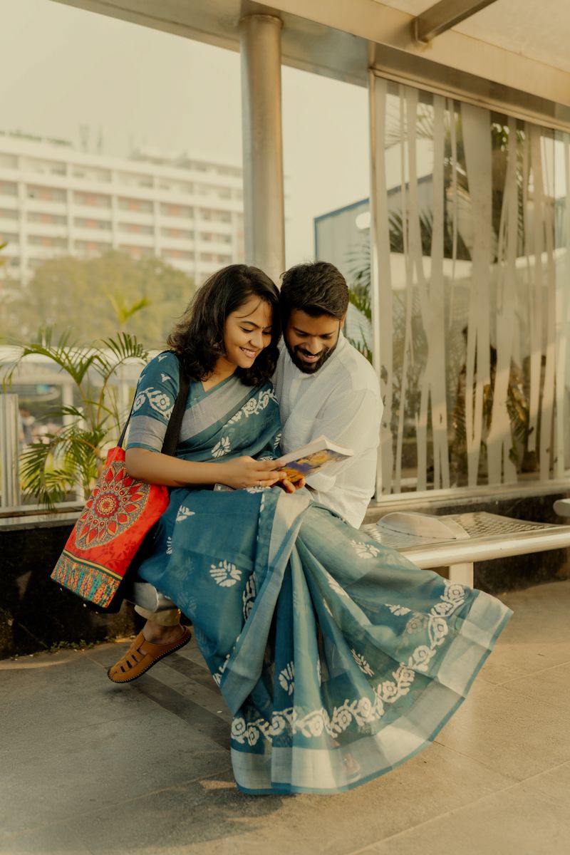 Two people in traditional Indian attire sharing a tender moment while looking at something together.