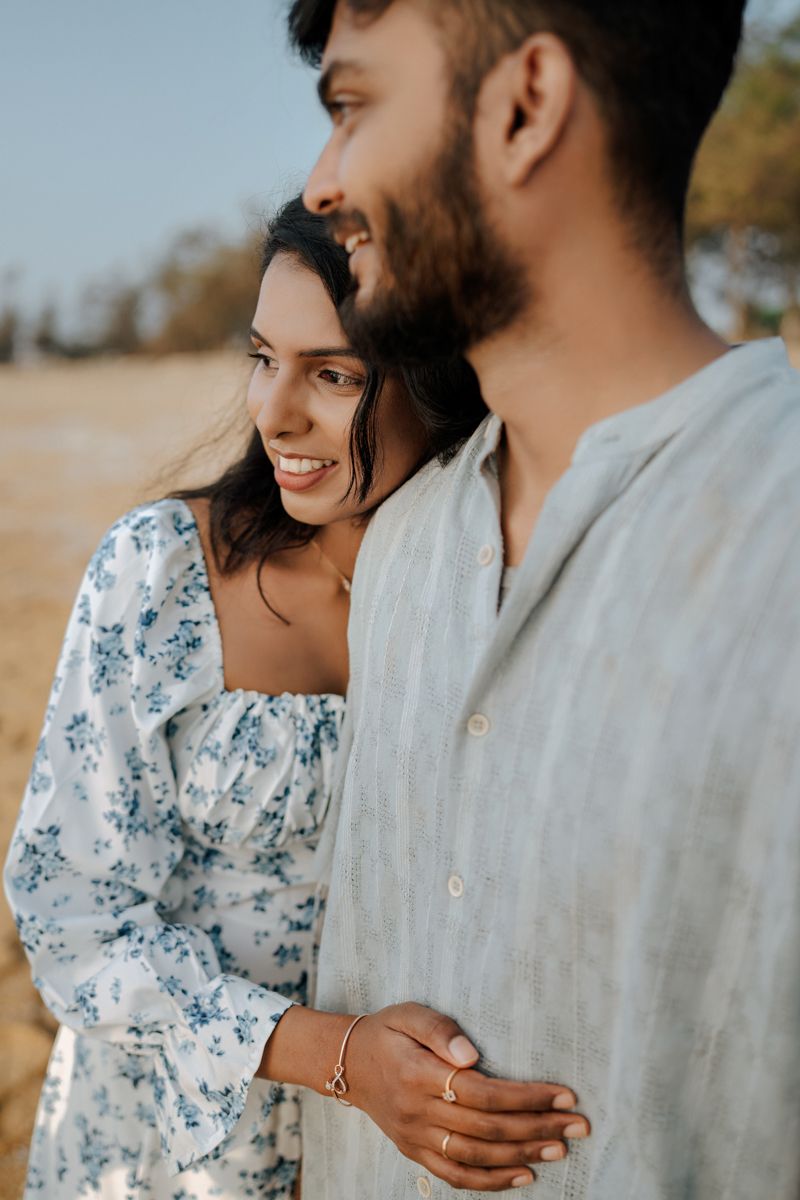 A romantic couple in matching blue and white outfits share an intimate moment outdoors.