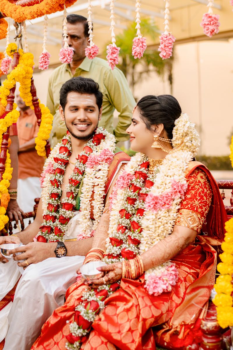 Traditional South Indian wedding ceremony with floral decorations and garlands in orange and pink.