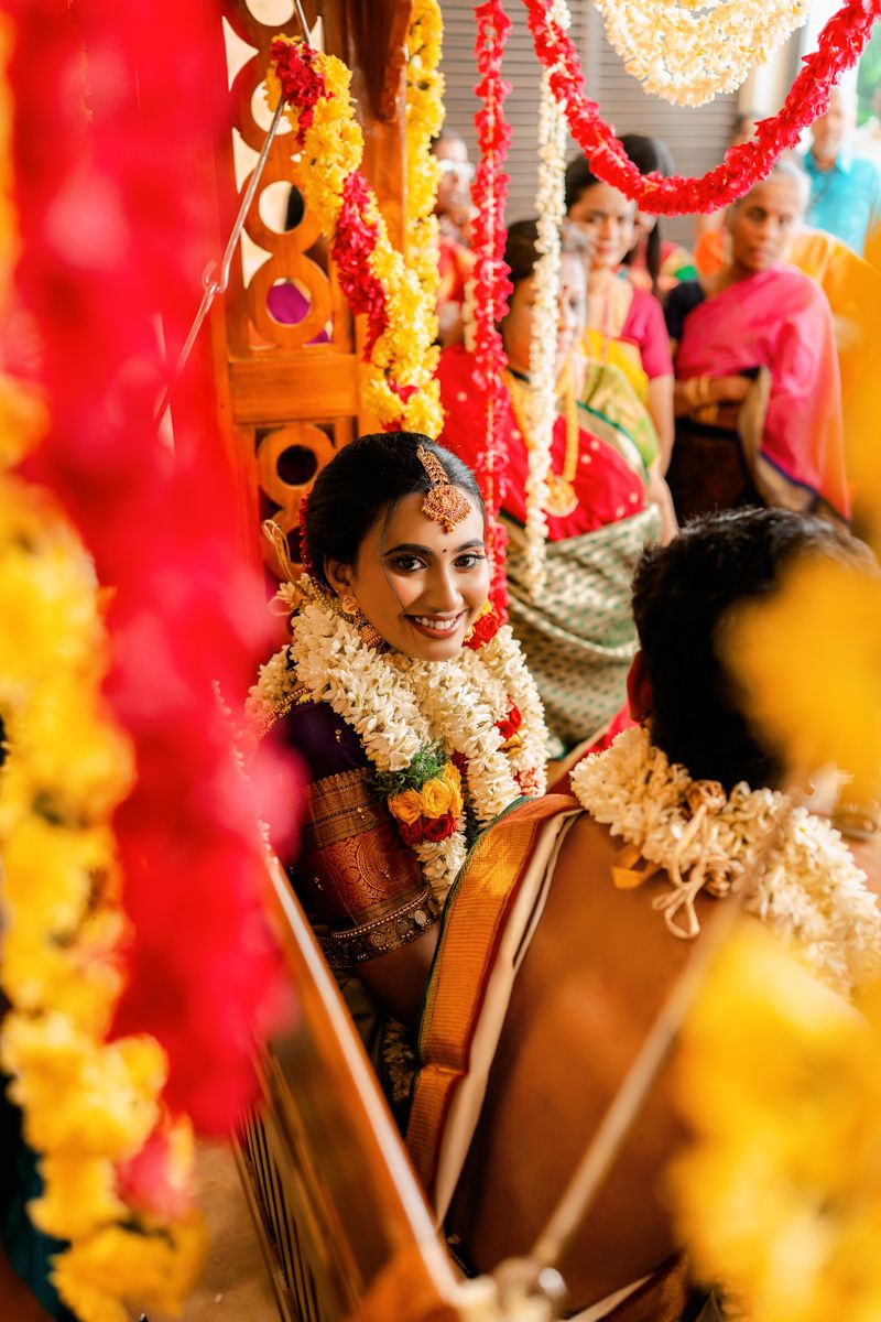 Wedding ceremony through decorative floral garlands showing traditional South Indian bridal look.