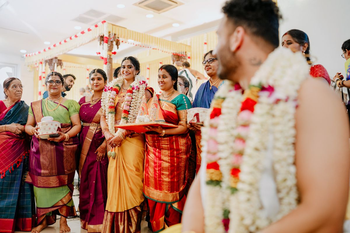 Traditional Indian wedding ceremony indoors with guests wearing colorful saris.
