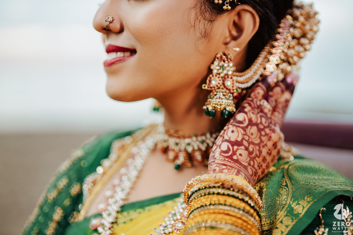 Close up of traditional South Indian bridal jewelry with gold earrings and floral hair accessories.