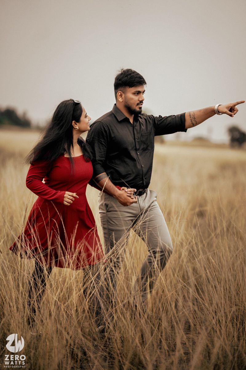 A couple in formal wear poses dramatically in a golden wheat field at sunset.