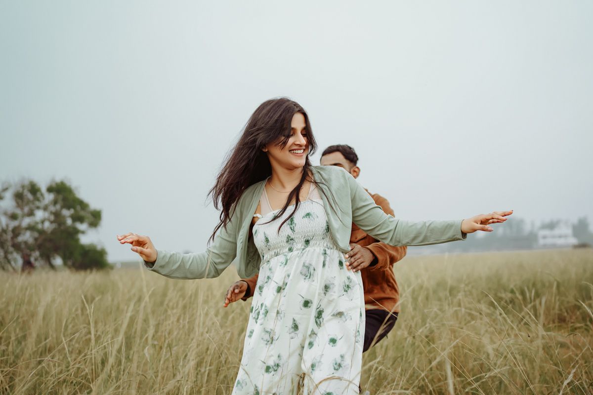 Two people enjoying a carefree moment together in a grassy field on an overcast day.