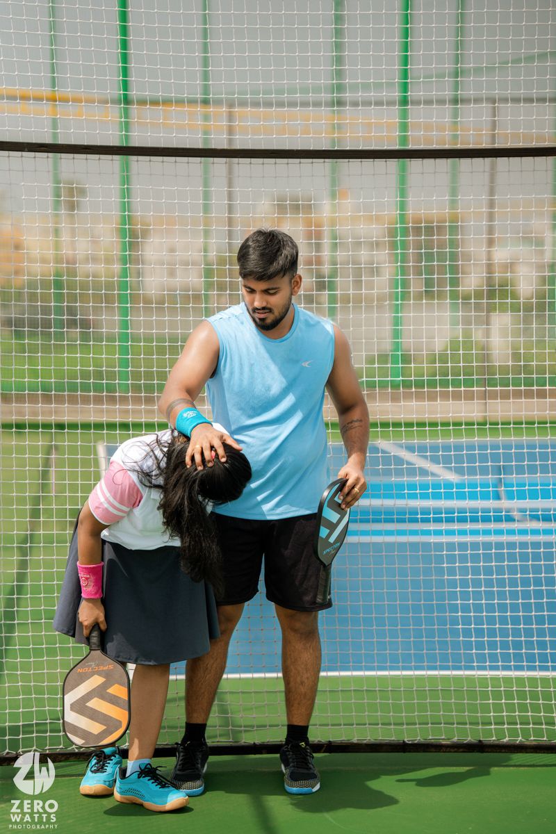 A couple in sporty outfits standing together on an outdoor sports court.