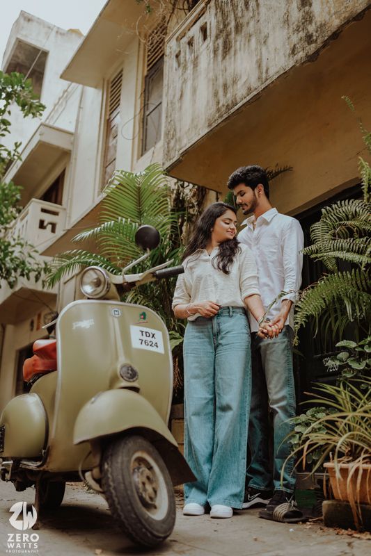 Romantic photo session with a classic Vespa scooter against an urban backdrop with lush greenery.