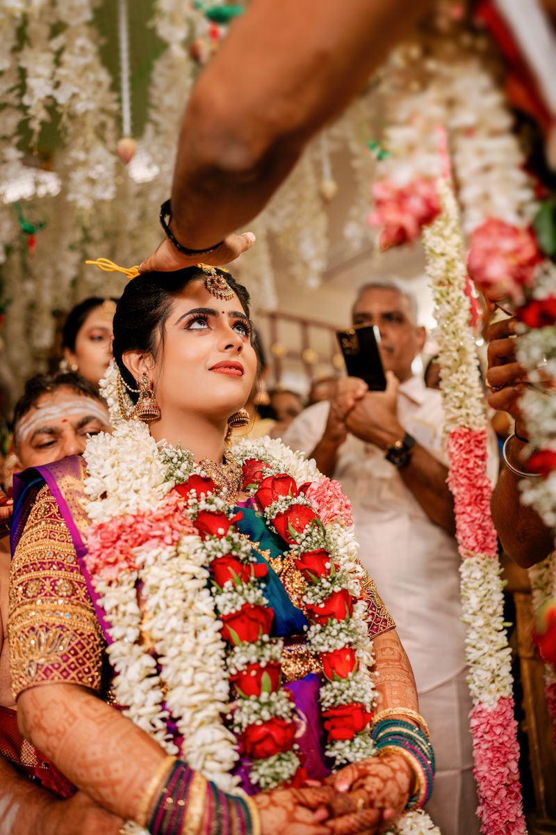 Traditional Indian bride wearing ornate jewelry and flower garlands during wedding ceremony.