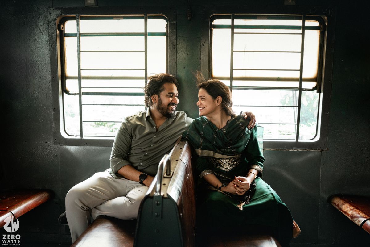Couple shares intimate moment while sitting together in train compartment by window in moody lighting.