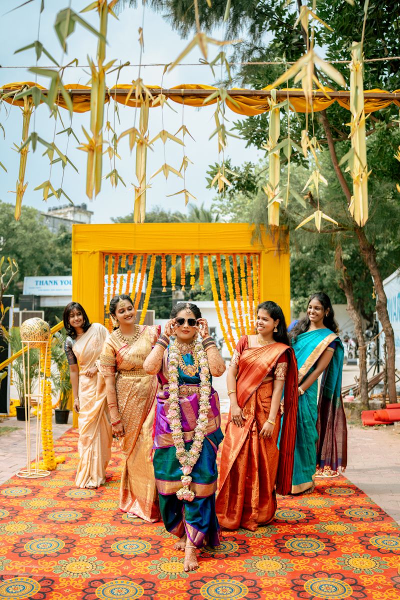 Wedding celebration with guests in colorful saris gathered under yellow decorations and bamboo ornaments.