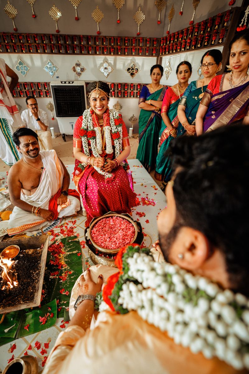 Traditional South Indian wedding ceremony with guests gathered around sacred offerings and flower petals on banana leaves.