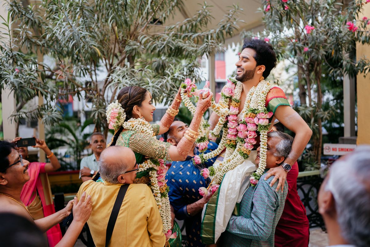 Wedding celebration scene with guests lifting and celebrating during traditional South Indian ceremony.