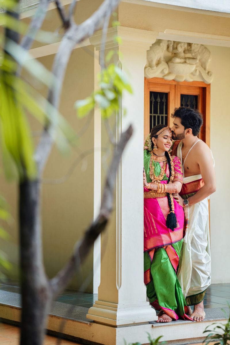 Traditional South Indian wedding couple pose in bright traditional attire on their wedding day.