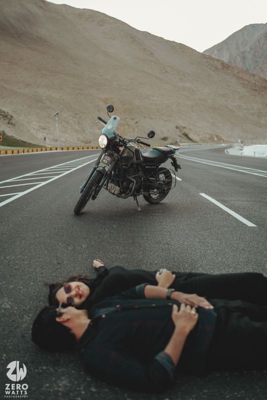 A parked motorcycle on an empty mountain highway with desert mountains in the distance.