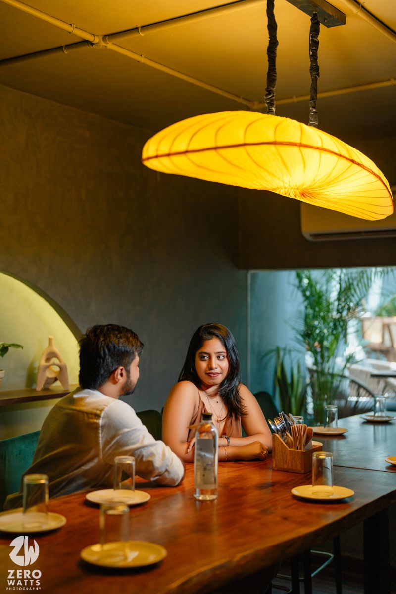 Romantic dinner scene at a wooden table under warm pendant lighting in a restaurant.