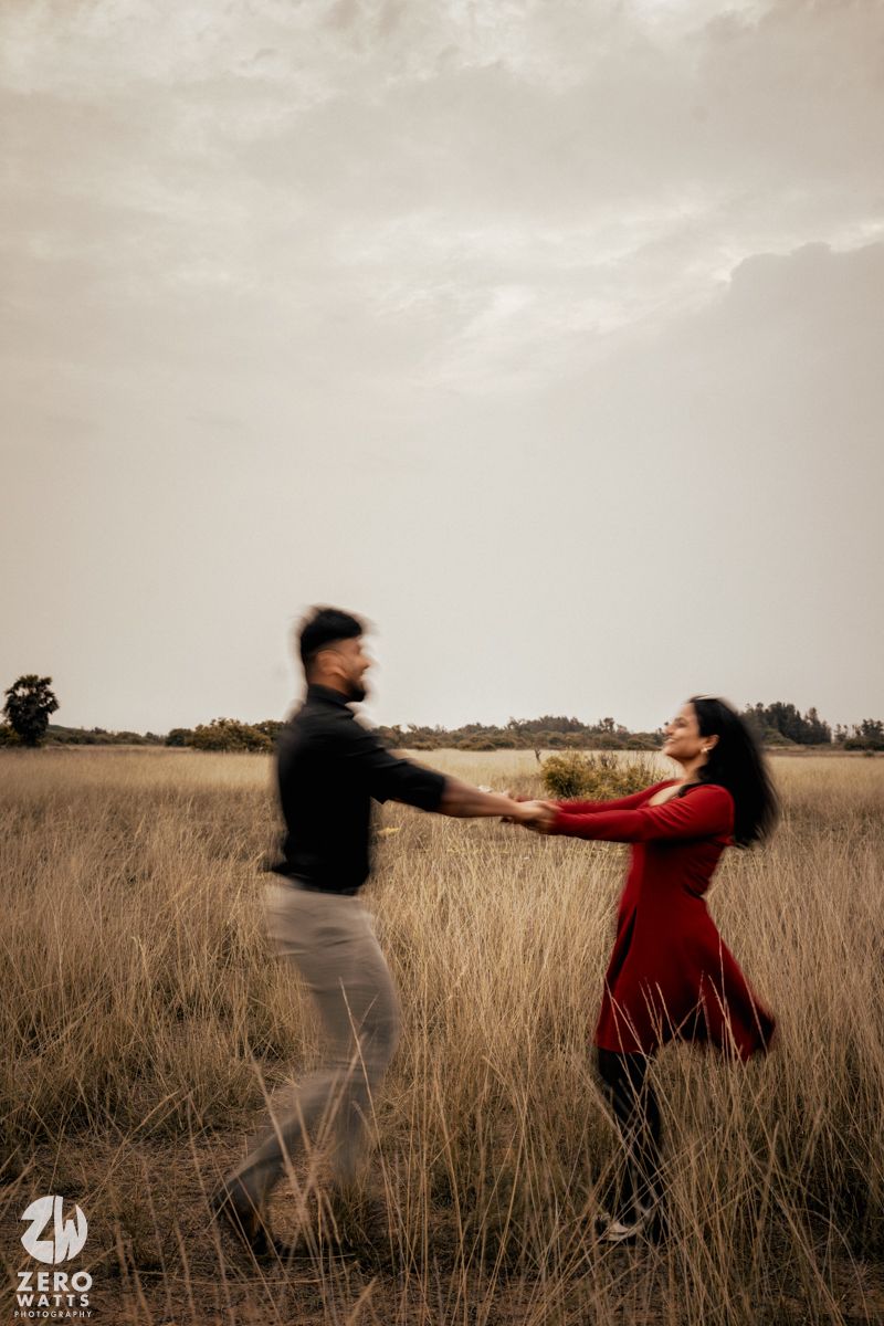 Couple dancing in a golden field with dramatic sky at sunset.