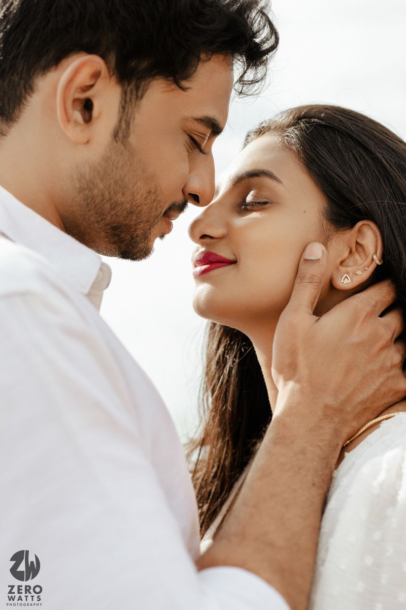 A tender close up of a couple in white clothing sharing an intimate romantic moment together.