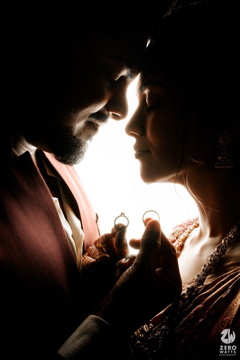 A dramatic silhouette photograph of a couple in an intimate moment with glowing backlighting creating a romantic atmosphere.