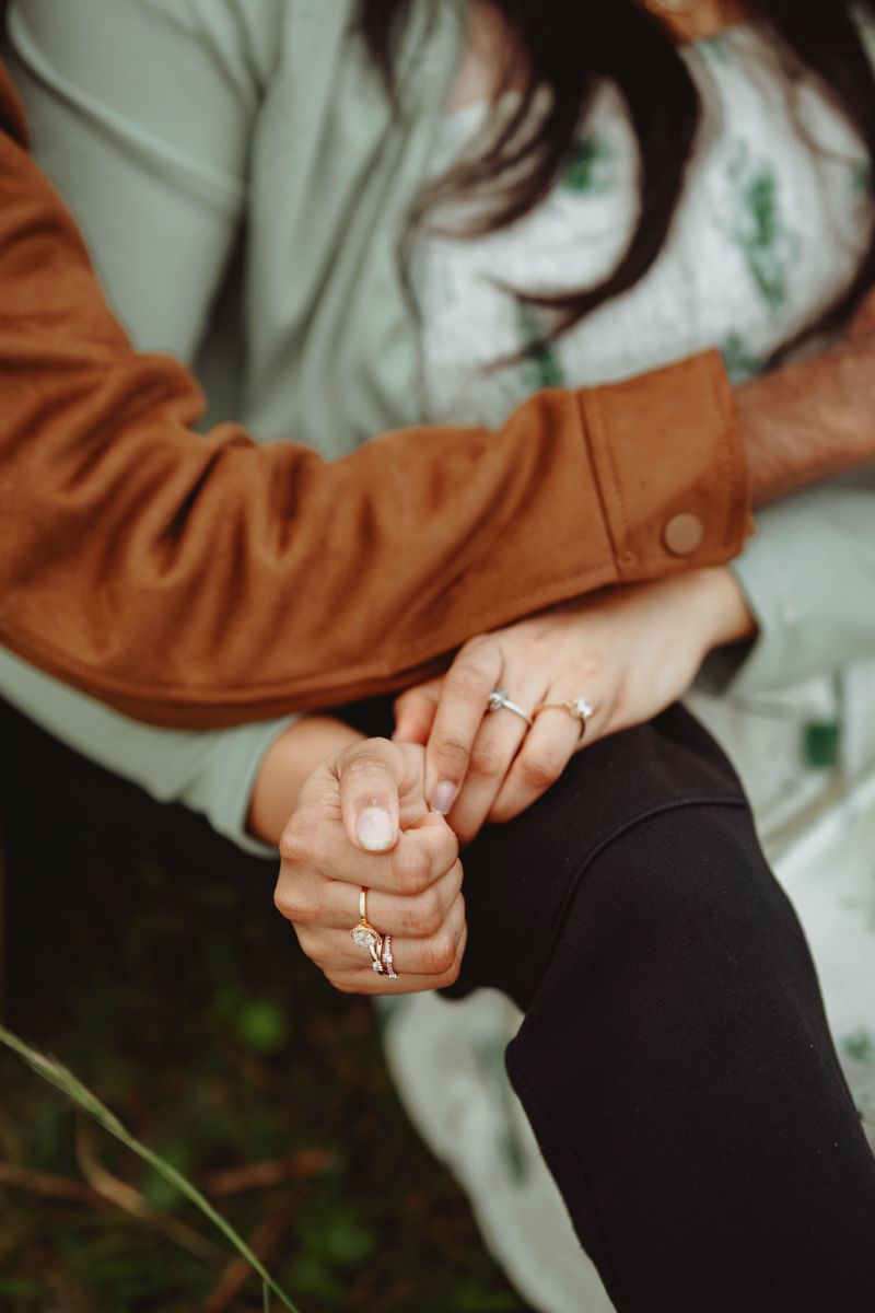 Close-up shot of hands with multiple rings in a romantic pose against a light background.