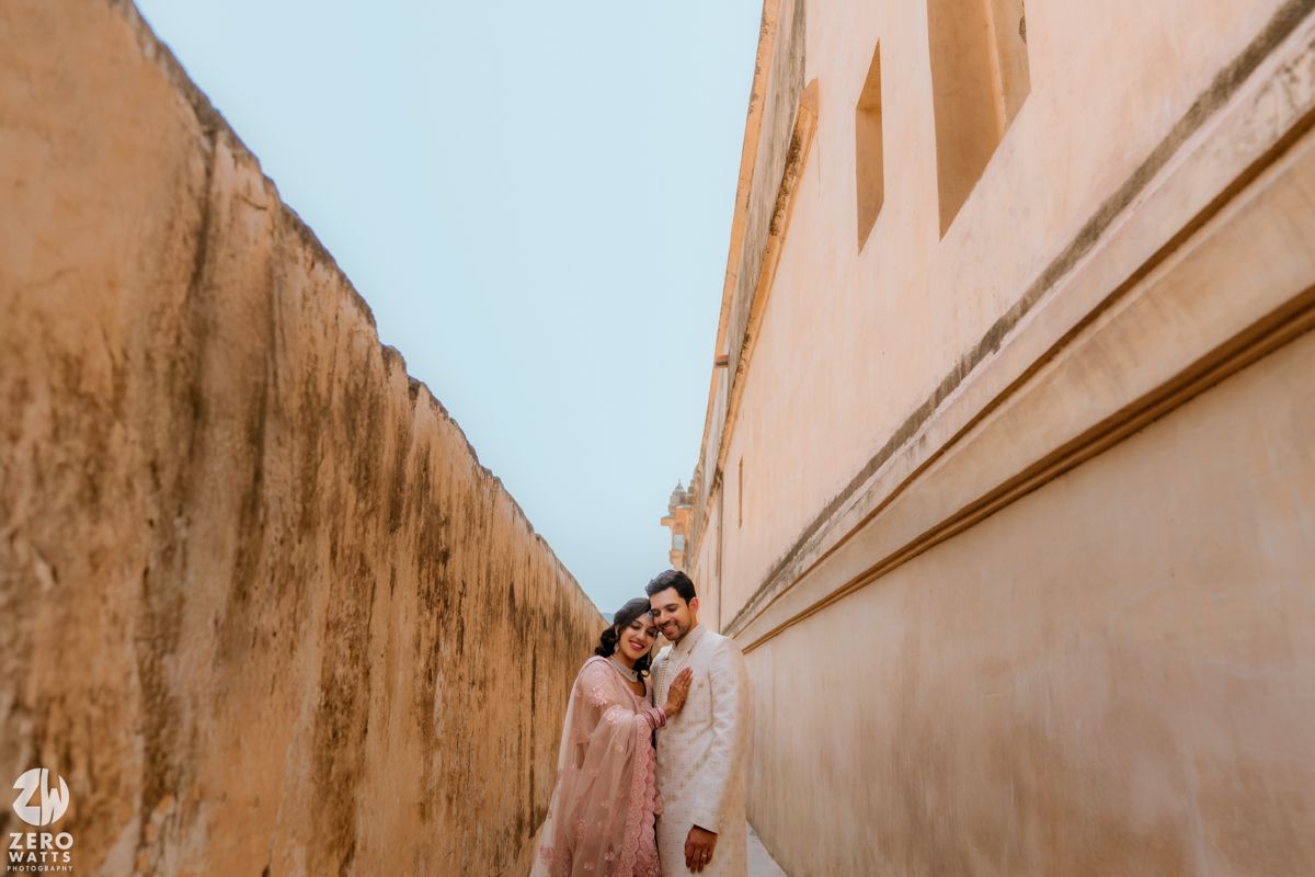 A couple poses together against weathered walls in a narrow alley with soft lighting.