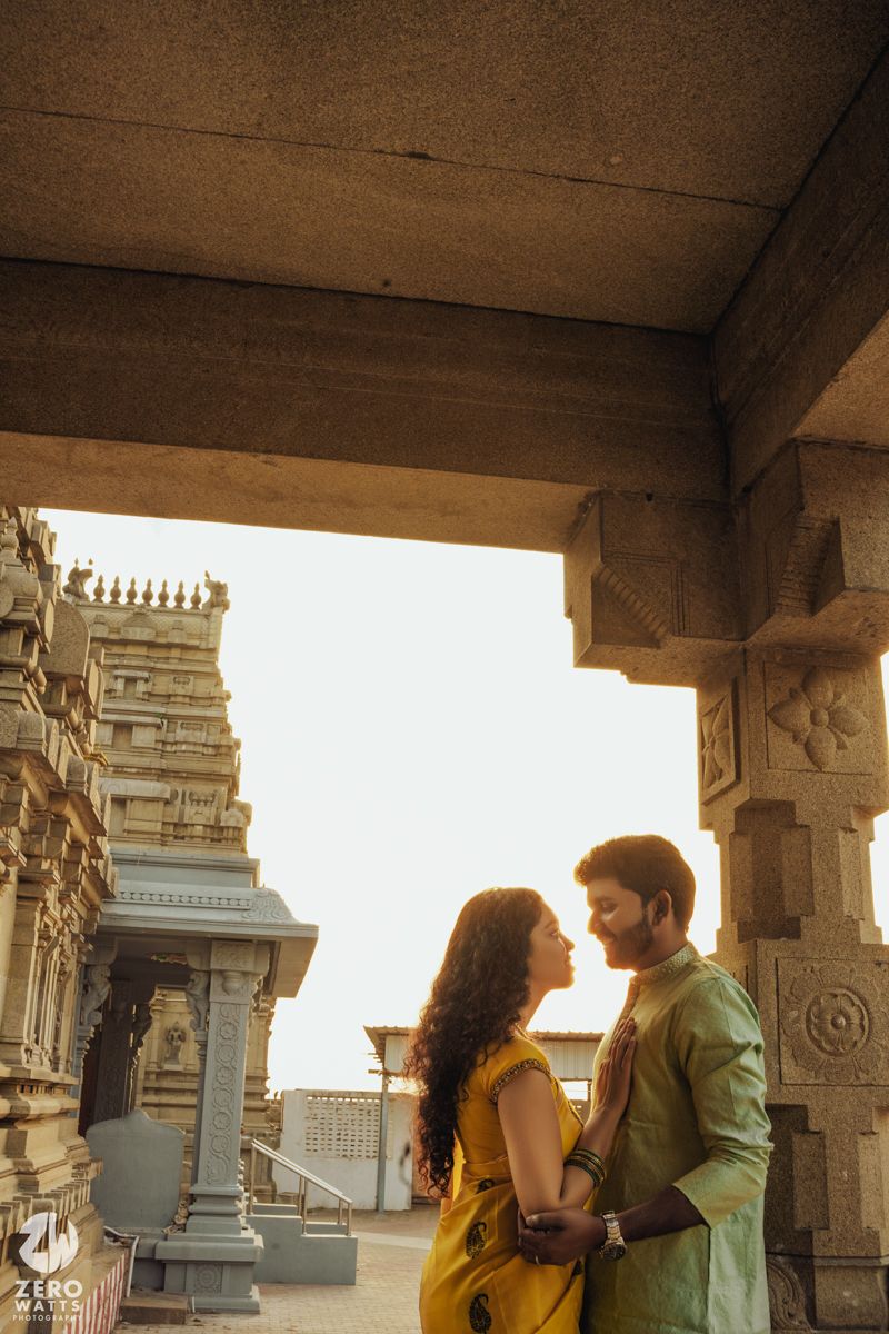 Intimate moment captured between couple at ancient temple with ornate pillars and architecture.