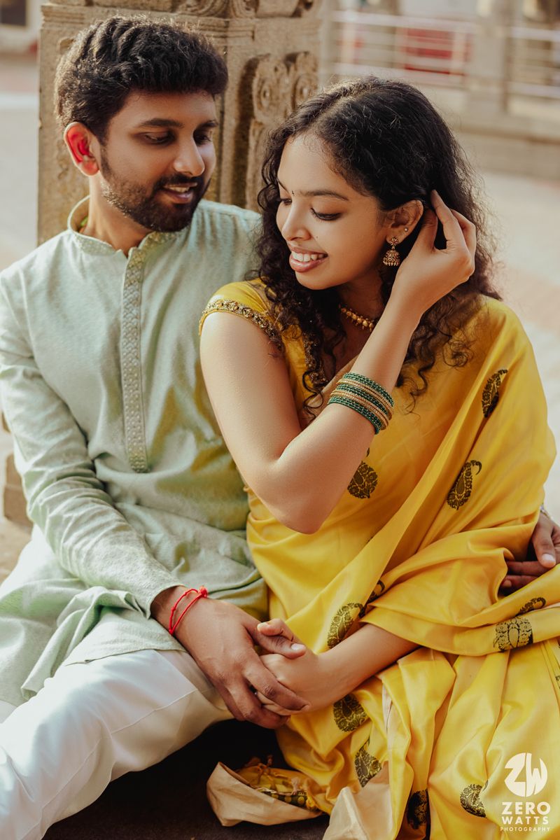 A tender moment captured in traditional Indian attire with yellow sari and mint green kurta.