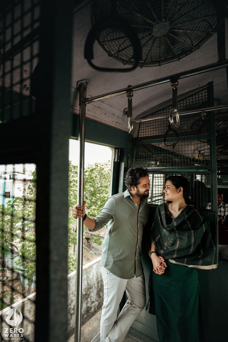 Couple sharing a moment near train windows with industrial fan visible above.