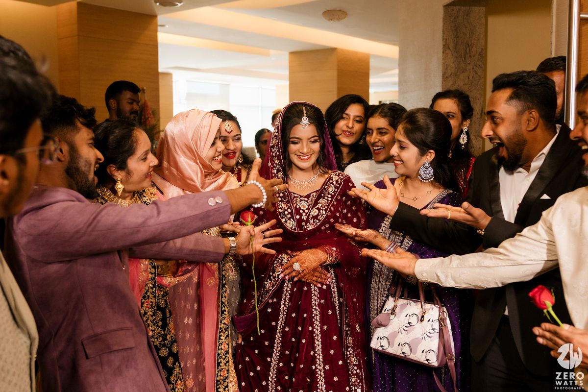 Joyful wedding celebration with guests surrounding the couple in traditional South Asian attire.