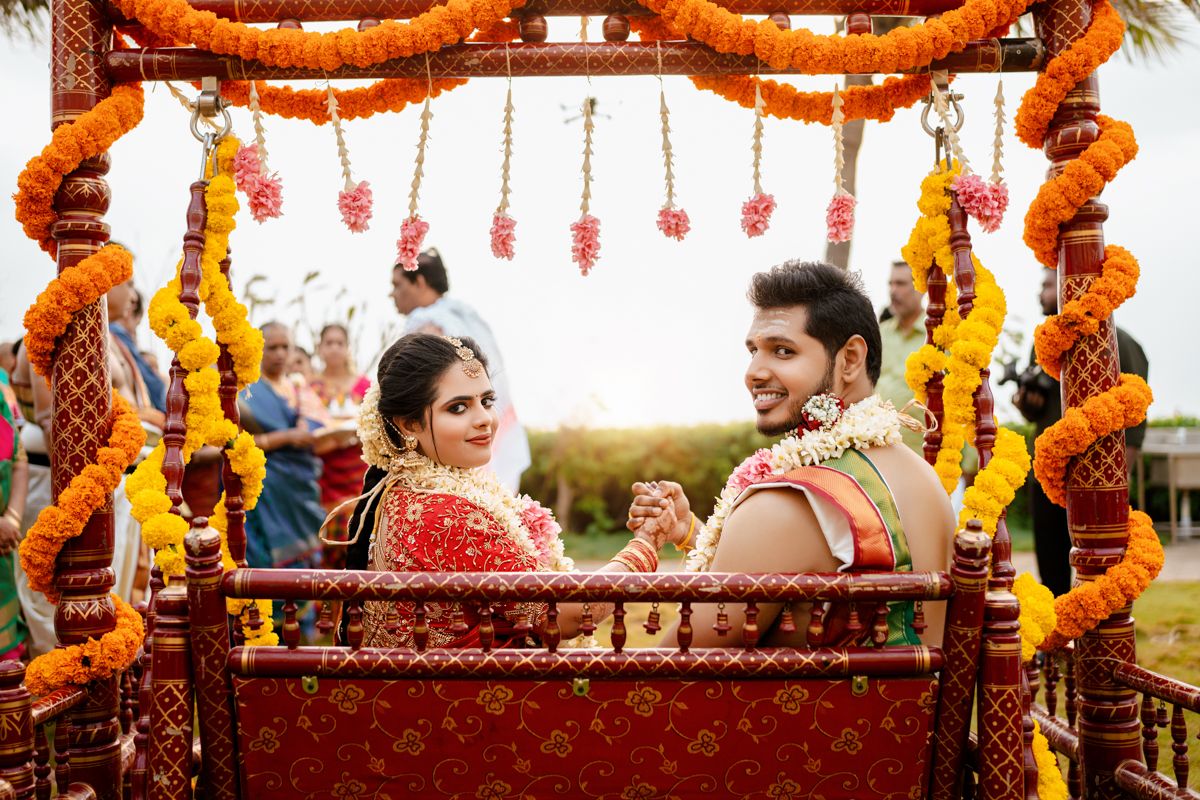 Traditional Indian wedding ceremony decoration with ornate marigold garlands and hanging flowers on an outdoor swing seat.