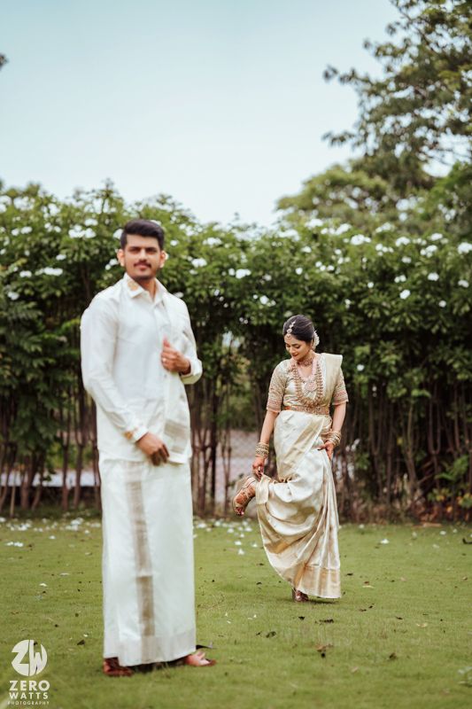 Couple in traditional dress sharing playful moments in garden setting.